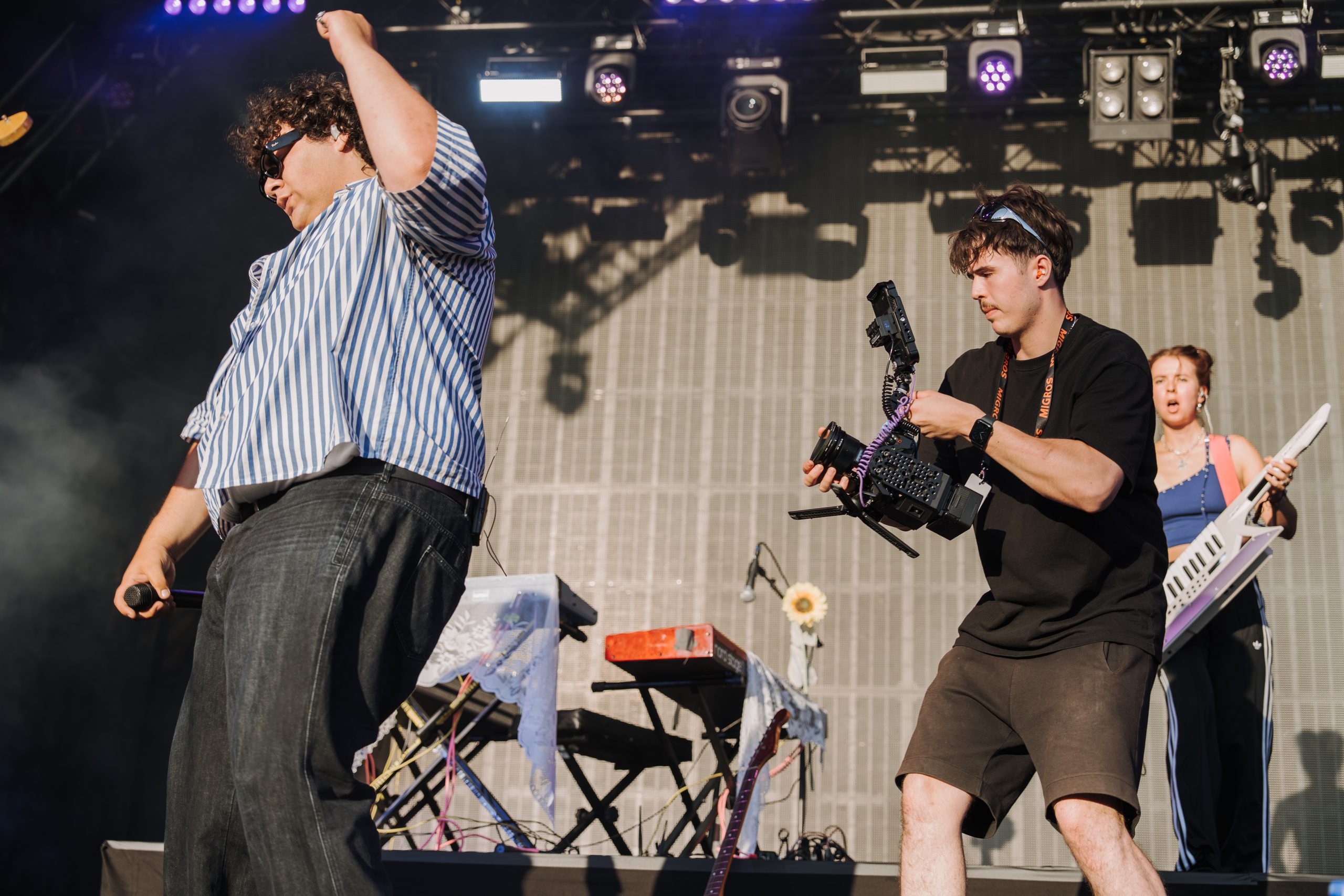 Janis Chatelain filmt mit der Kamera auf einer Festivalbühne